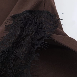 Detail of dark brown twill fabric stitched with delicate black eyelash lace trim