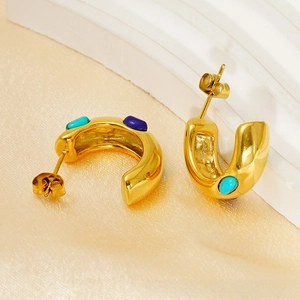 Detailed close-up of golden C-shaped earrings with inlaid turquoise and blue stones