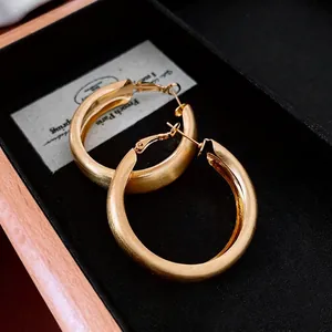 Minimalist thick gold hoop earrings with a brushed finish and elegant silver needles
