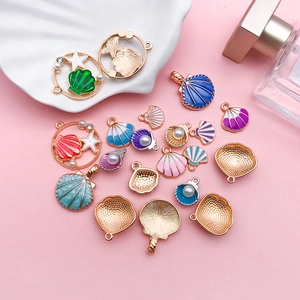 Detailed close-up of alloy shell pendants with colorful enamel and pearl accents on pink background