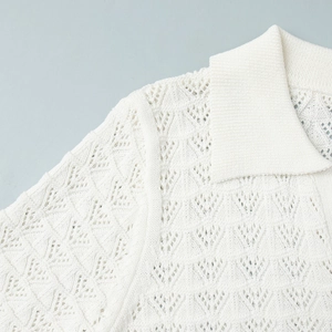 Detail view of white knit polo shirt featuring intricate hollow diamond geometric patterns