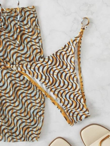 Flat lay detail of bikini with orange and blue retro wave pattern on marble surface