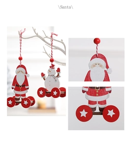 Detail of wooden Santa and Snowman ornaments with red star wheels hanging on white branches