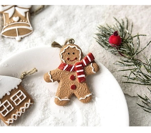 Close-up of resin gingerbread man and bell charms on artificial snow with pine branch