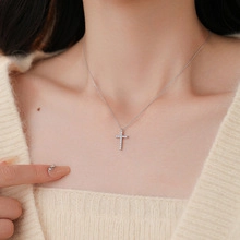 Dettaglio di una collana a croce in argento con zirconi colorati sulla clavicola