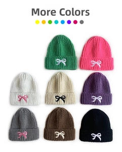 Detailed embroidery of sweet bows on multi-colored warm knitted beanies for kids