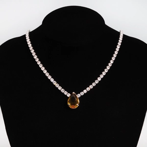 Detail of tennis chain necklace with a pear-cut amber zircon pendant on black velvet