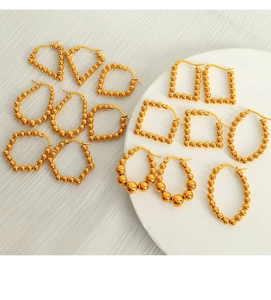 Detailed close-up of golden geometric titanium earrings in various shapes on a tray
