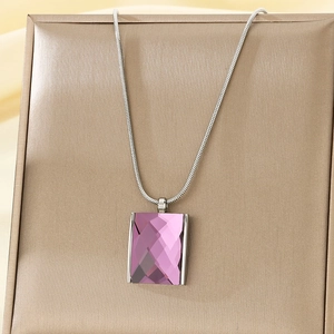 Close-up of a purple rectangular crystal pendant with a silver snake chain on silk