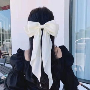 Elegant large cream bow hair clip with long satin ribbons shown on woman hair