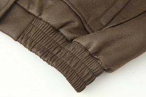 Macro shot of dark brown faux suede jacket featuring ribbed elastic hem and fine stitching