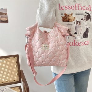 Sac en toile matelassé rose à motif lapin porté par un mannequin en style décontracté