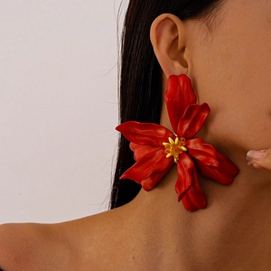 Close-up of a large red acrylic flower earring with yellow beaded center worn by a model