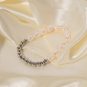 Détail d'un bracelet en perles d'eau douce et perles de métal sur tissu de soie beige