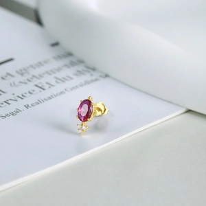 Macro shot of S925 silver gold-plated earring with oval red gemstone and accent diamonds
