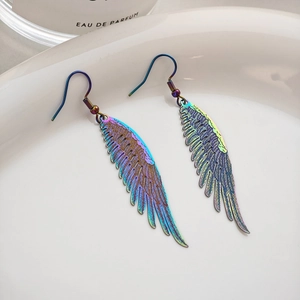 Detailed close-up of rainbow gradient feather earrings on a white ceramic tray