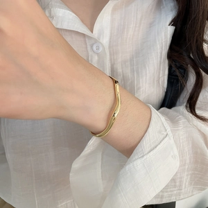 Detail shot of wavy 18k gold plated bracelet with a high-shine mirror finish on wrist