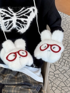 Close-up of white plush bunny crossbody bag with red glasses and shoulder strap detail