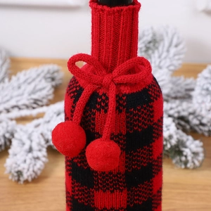 Détail du cache-bouteille de vin tricoté à carreaux rouges et noirs avec pompons doux