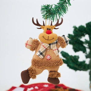 Detail of a plush reindeer Christmas ornament with red plaid scarf on a green tree branch