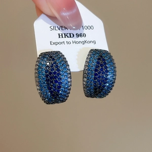 Close-up of C-shaped 1000 silver stud earrings with gradient blue pavé zircons