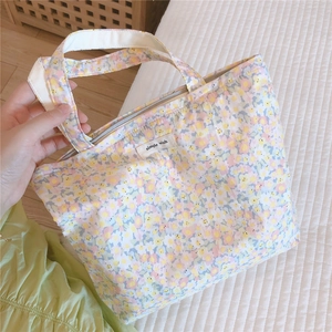 Gros plan du sac en coton fleuri avec fermeture éclair et détail de l'étiquette simple