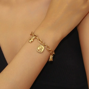 Close-up of 18K gold-plated bracelet with rose and character charms on model wrist