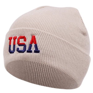 Close-up of USA embroidery on beige ribbed knit beanie with red and blue stitching