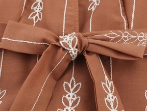 Détail de la broderie et du nœud à la taille sur une robe longue ethnique sans manches