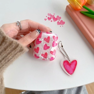 Detail view of pink heart pattern AirPods case with a matching heart charm accessory