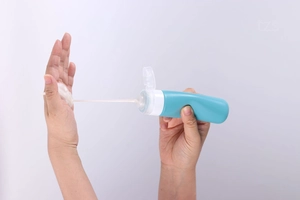 Silicone travel bottle dispensing white cream texture showing squeeze functionality