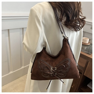 Détail du sac à bandoulière en daim marron foncé avec appliqué papillon et lacets