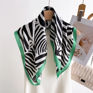 Fashionable zebra print silk scarf with green borders hanging on a wooden hanger