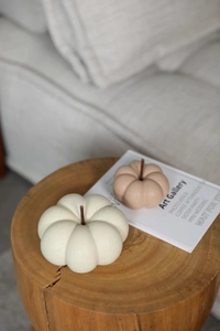 Detail of matte ceramic pumpkin decor pieces on a wooden base with artistic card accents