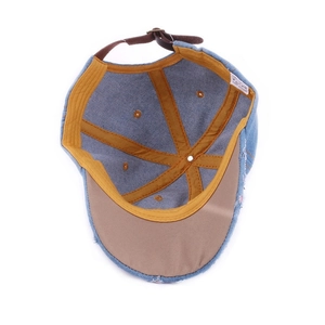 Internal view of blue denim baseball cap showing yellow stitching and leather strap