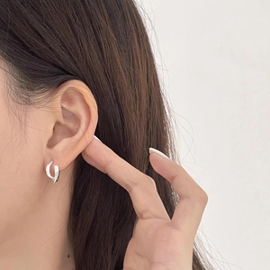 Close-up of elegant S925 sterling silver knotted hoop earrings worn by a model