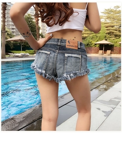 Rückansicht sexy Denim-Shorts mit Fransen und Taschen vor einem Pool-Hintergrund