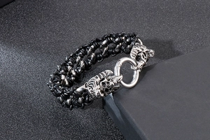 Close-up of double tiger head buckle with stainless steel clasp on woven leather bracelet