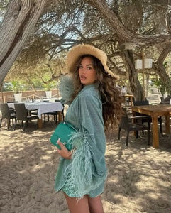 Détail de chemise de vacances verte avec poignets en plumes et short à paillettes