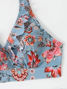 Dettaglio del top bikini azzurro con stampa floreale e volant sullo scollo a v profondo