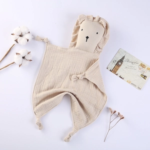 Detail of soft muslin baby comforter with lion plush toy and knotted corners