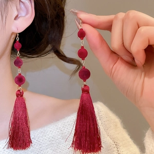 Detail of red flocked bead earrings with silk tassels on a model for a festive look