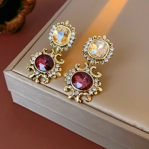 Vintage gold earrings set with amber and ruby crystals and small rhinestones in beige box