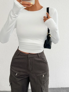 Detailed close-up of white slim-fit long-sleeve knit top with elegant crew neckline for women