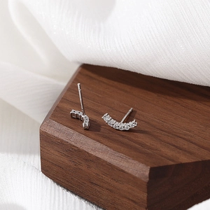 S925 Sterling Silver curved smile stud earrings with pavé zircons on a wooden stand