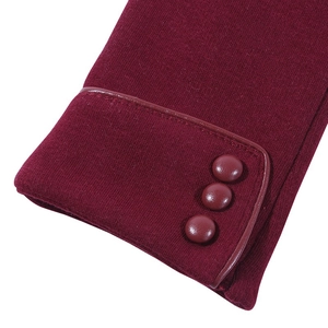 Detail of wine red winter gloves showing smooth knit texture and three decorative glossy buttons