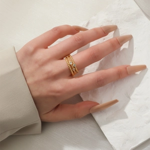 Elegant gold-plated wide band ring with zircon accents on a textured stone background