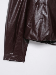 Detailed macro view of burgundy faux leather jacket featuring premium stitching and texture