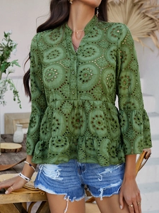 Détail du tissu à broderie ajourée verte avec col en V et ourlet à basque sur une chemise femme