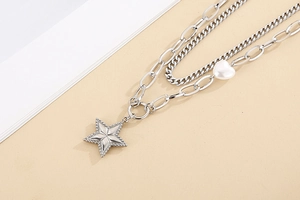 Detail of silver double-layer stainless steel necklace with white heart and star pendants